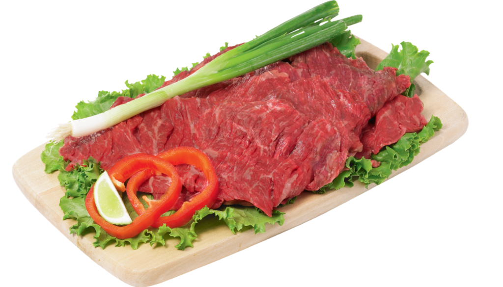Flap meat ranchera with green onion and red pepper garnish on a bed of lettuce on a wooden cutting board