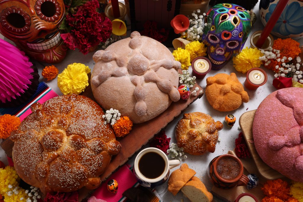 Pan de Muerto on a wooden platter with smaller versions surrounding it