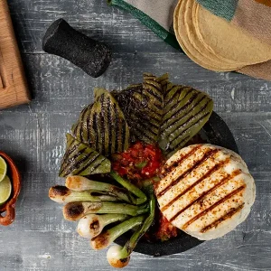 Molcajete filled with grilled nopales, green onions, cheese, and salsa