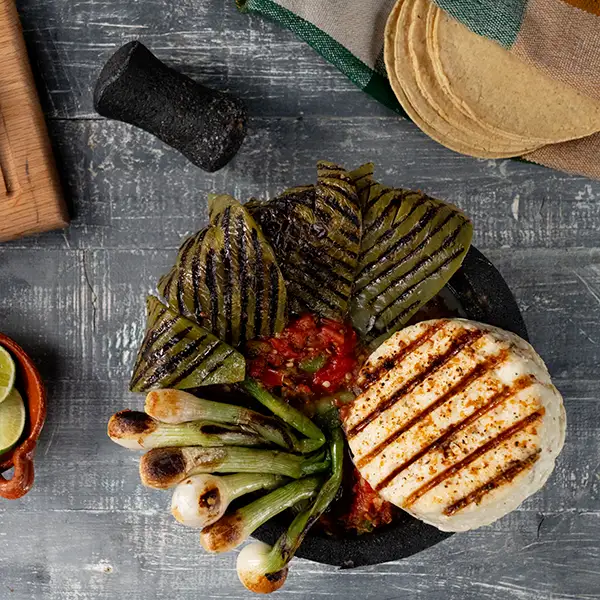 Molcajete filled with grilled nopales, green onions, cheese, and salsa