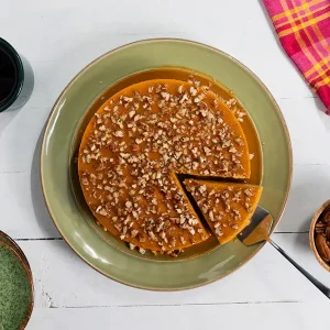 Flan with pecans sprinkled on top, served on a plate