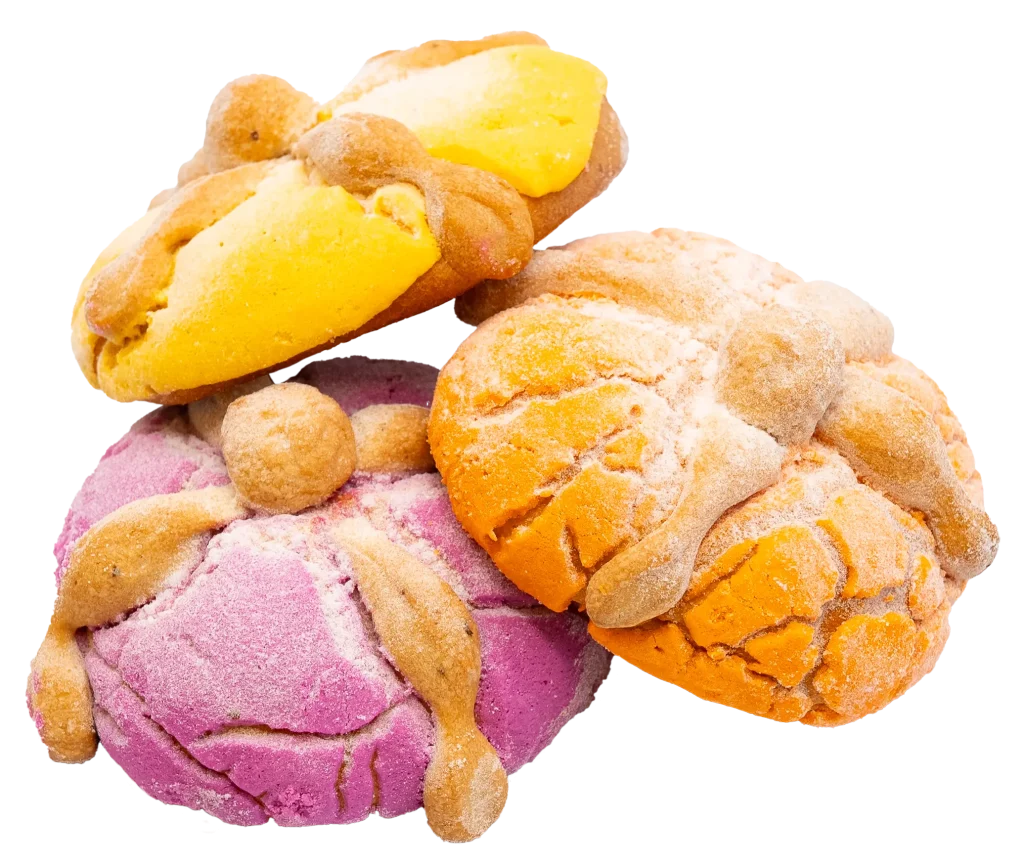 Three colorful pan de muerto breads in yellow, orange, and pink, dusted with sugar and decorated with bone-shaped dough.