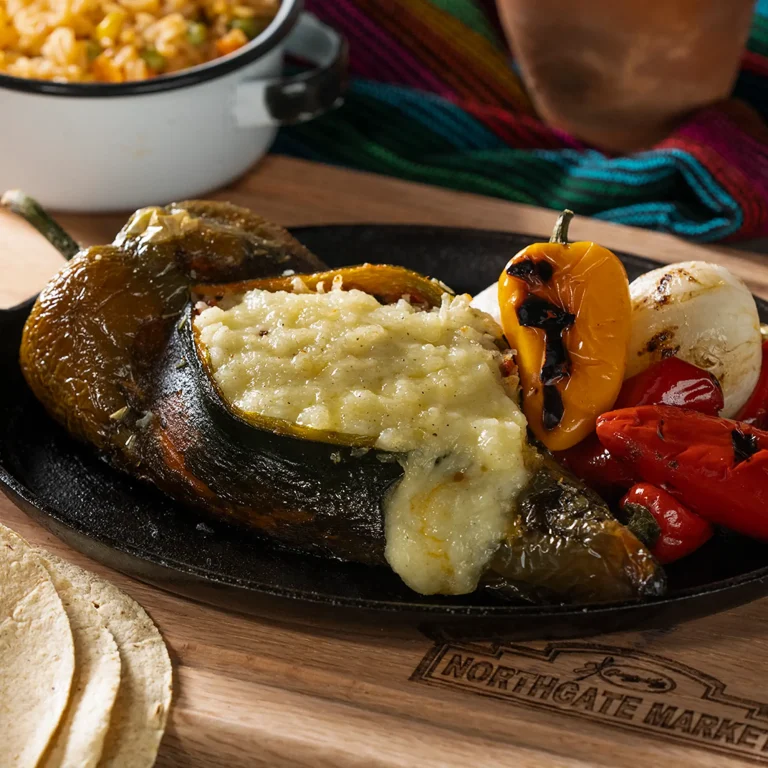 Pasilla chile relleno stuffed with chorizo and melted asadero cheese, served with grilled peppers and onion on a cast iron skillet.